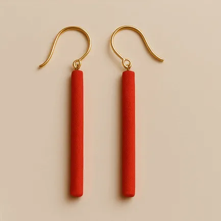 Long red dangle earrings with slim cylindrical shape and gold hooks